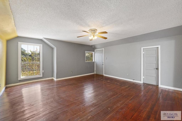 interior space with vaulted ceiling, ceiling fan, dark hardwood / wood-style flooring, and a textured ceiling