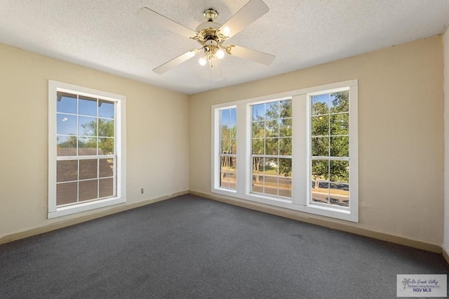 unfurnished room with a wealth of natural light, dark carpet, and a textured ceiling