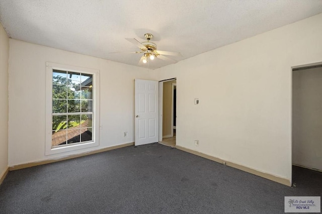 carpeted empty room featuring ceiling fan and a textured ceiling