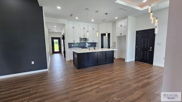 kitchen with a kitchen island with sink, dark hardwood / wood-style flooring, and decorative light fixtures