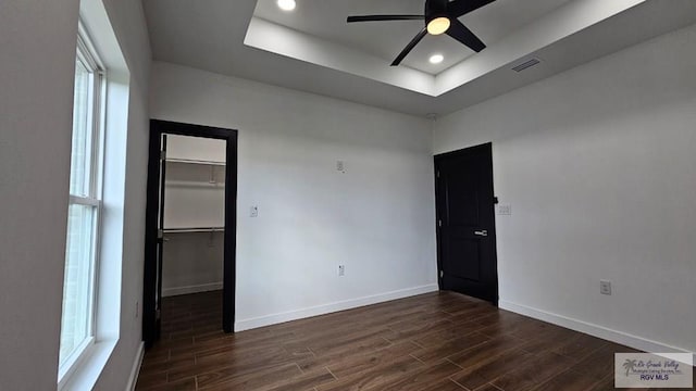 spare room with a raised ceiling, ceiling fan, plenty of natural light, and dark hardwood / wood-style floors