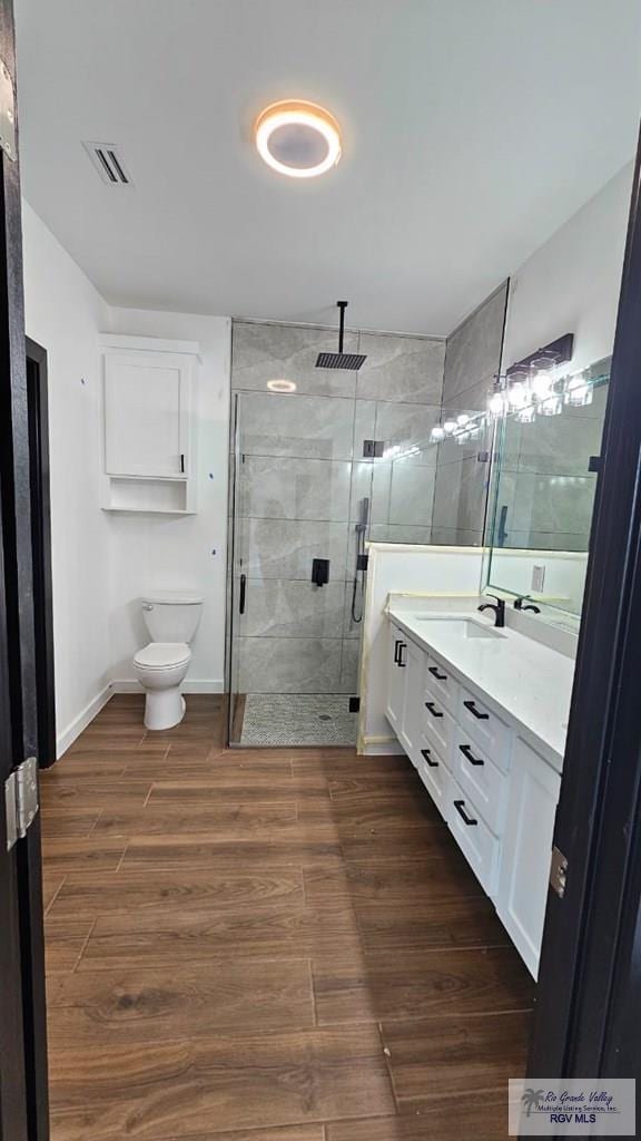 bathroom with vanity, toilet, wood-type flooring, and a shower with door