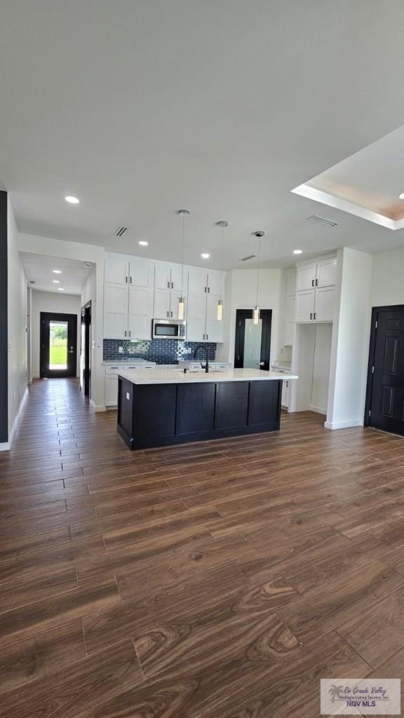 kitchen with dark hardwood / wood-style flooring, decorative light fixtures, white cabinetry, and a large island