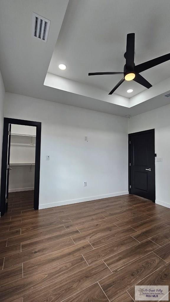 spare room with a raised ceiling, ceiling fan, and dark wood-type flooring