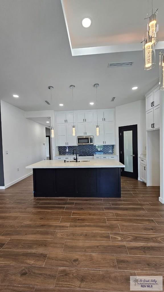 kitchen featuring a large island, decorative light fixtures, white cabinets, and dark wood-type flooring