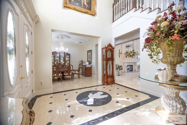 foyer entrance featuring plenty of natural light, a towering ceiling, and a chandelier