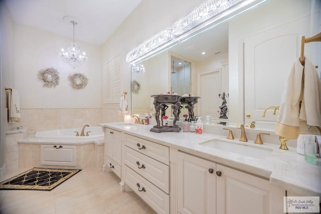 bathroom with tile patterned flooring, vanity, a chandelier, and tiled tub