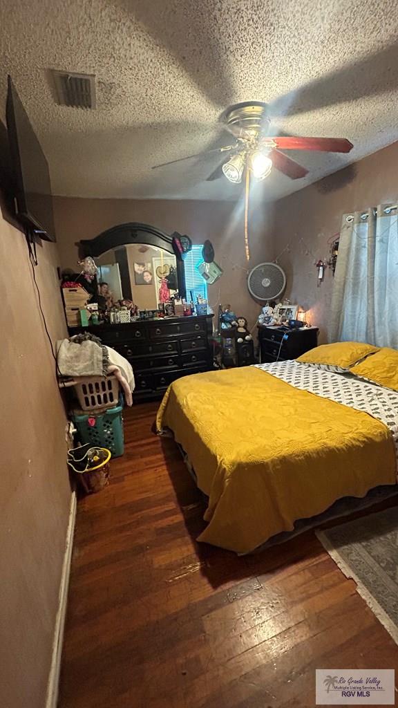 460 E Hicks St, San Benito, TX 78586 - bedroom with a textured ceiling, dark hardwood / wood-style flooring, and ceiling fan
