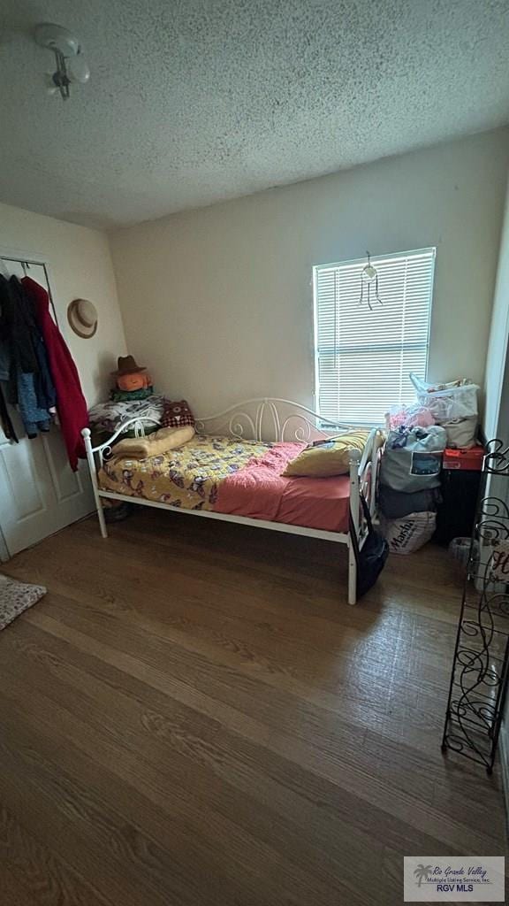 bedroom featuring dark hardwood / wood-style flooring and a textured ceiling