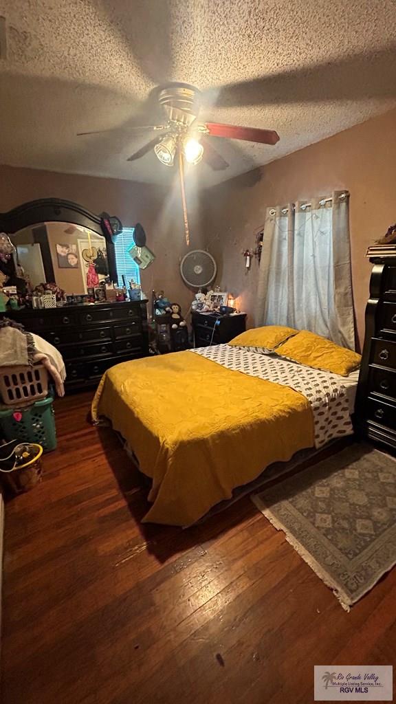 bedroom featuring a textured ceiling, ceiling fan, and dark wood-type flooring