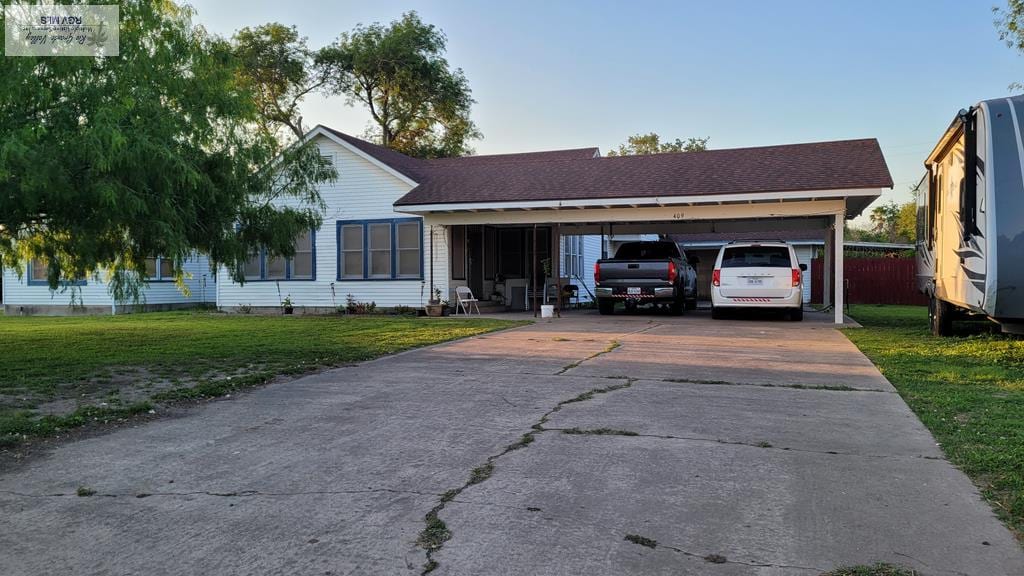 ranch-style home with concrete driveway, a carport, and a front lawn