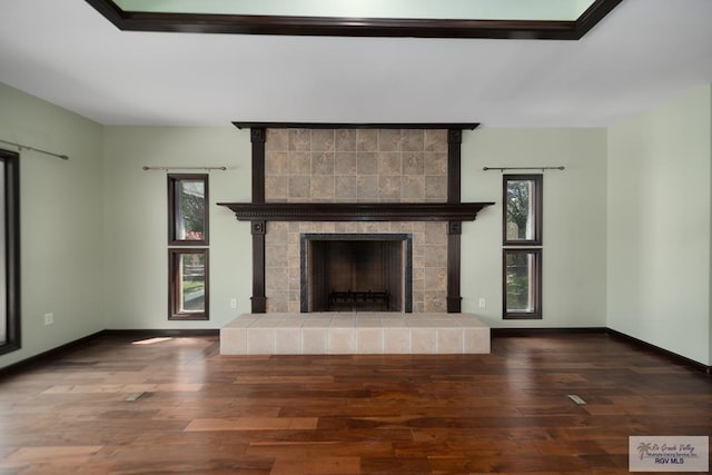 unfurnished living room with plenty of natural light, a fireplace, and dark wood-type flooring