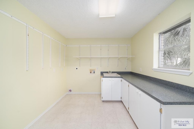 laundry room with sink, cabinets, washer hookup, electric dryer hookup, and a textured ceiling