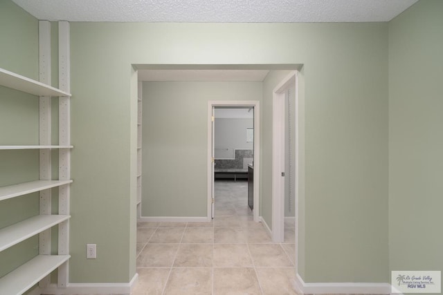 corridor with a textured ceiling and light tile patterned flooring