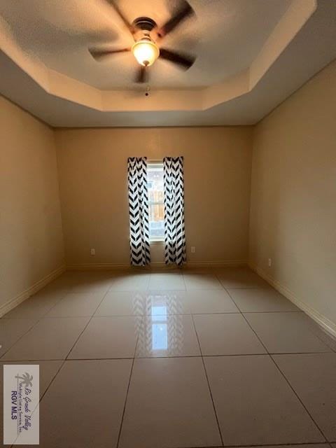 1972 Baja Dr Unit 4, Los Fresnos, TX 78566 - spare room featuring a tray ceiling, baseboards, light tile patterned flooring, and ceiling fan