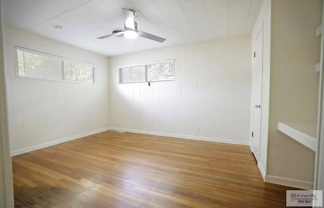 unfurnished room featuring ceiling fan, wood-type flooring, and wood walls