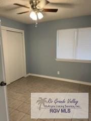 unfurnished bedroom with ceiling fan, tile patterned floors, and a closet