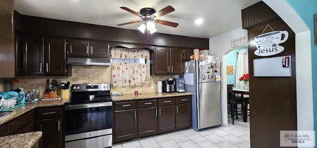 kitchen with dark brown cabinets, a ceiling fan, under cabinet range hood, appliances with stainless steel finishes, and tasteful backsplash