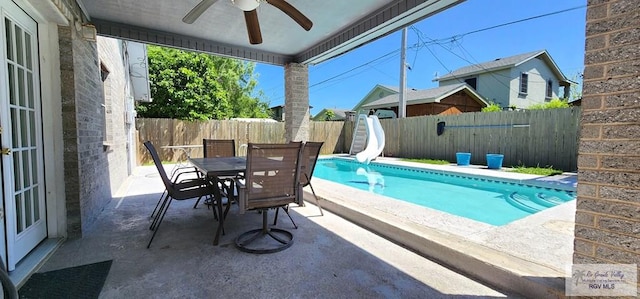 view of pool with outdoor dining space, a water slide, a fenced backyard, ceiling fan, and a fenced in pool