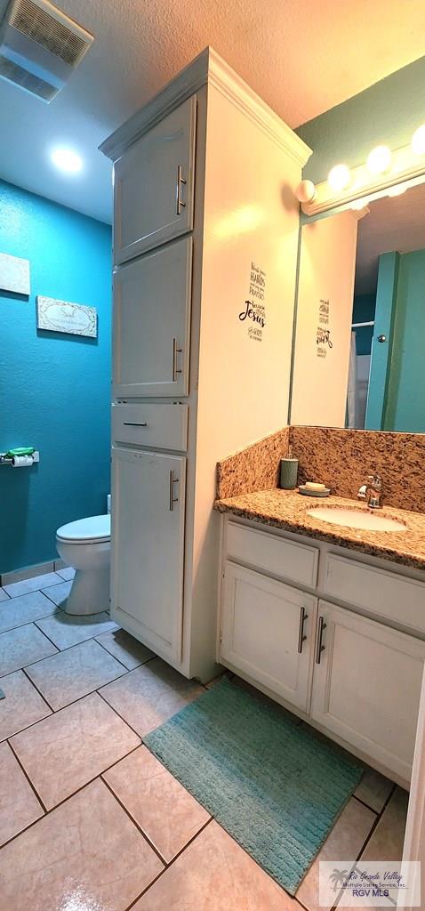 full bathroom with toilet, visible vents, tile patterned flooring, and vanity