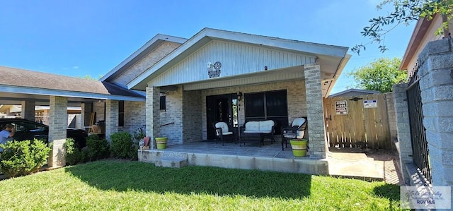 rear view of house featuring brick siding, fence, a lawn, and a porch