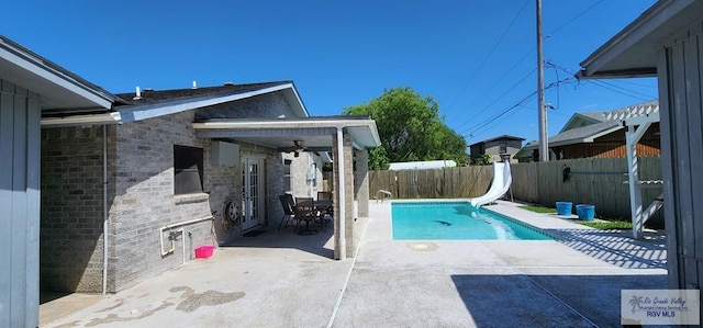 view of swimming pool with a fenced backyard, a patio, a fenced in pool, and a water slide