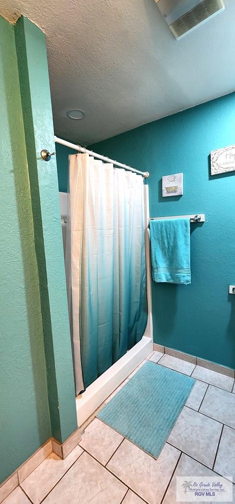 full bathroom with a shower with curtain, tile patterned flooring, and a textured ceiling