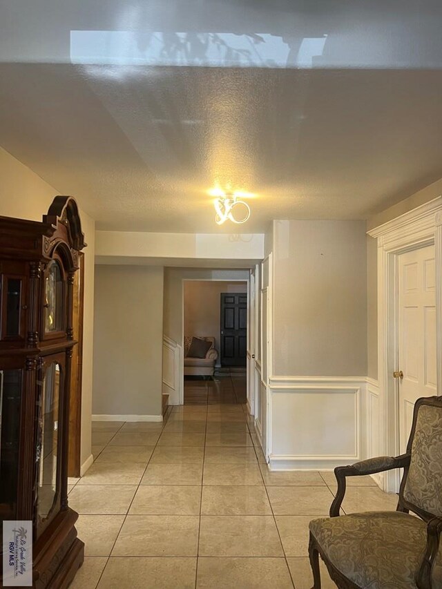 hallway with light tile patterned floors and a textured ceiling