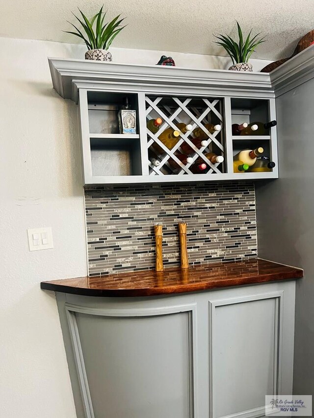 bar featuring decorative backsplash and a textured ceiling