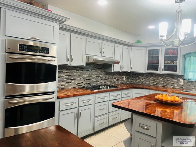 kitchen with decorative backsplash, wooden counters, light tile patterned flooring, and stainless steel appliances