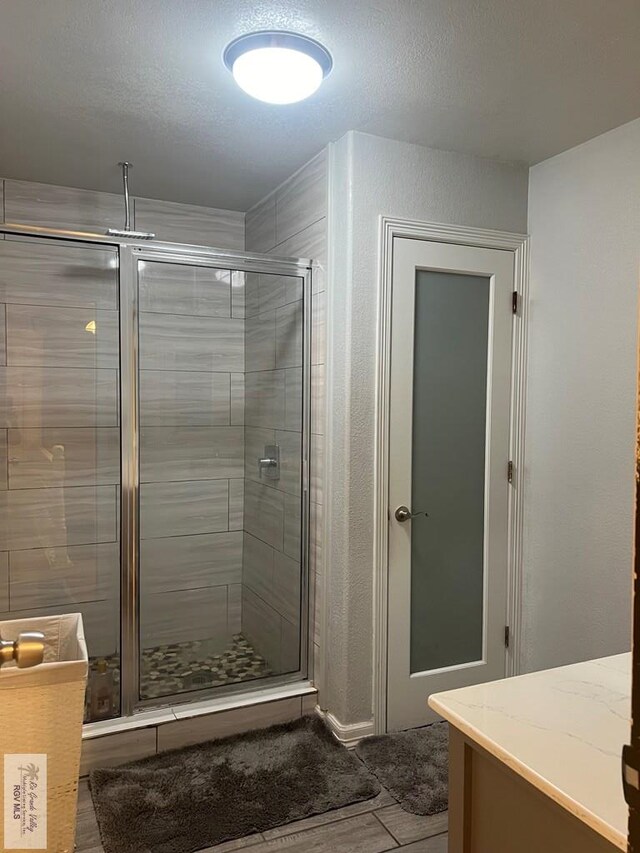 bathroom with vanity, a textured ceiling, and walk in shower