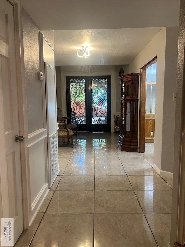 hall featuring french doors, a textured ceiling, and light tile patterned flooring