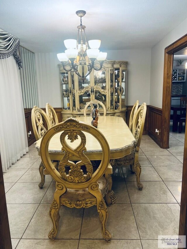 tiled dining room with wood walls and an inviting chandelier