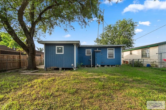 rear view of house with a fenced backyard and a yard
