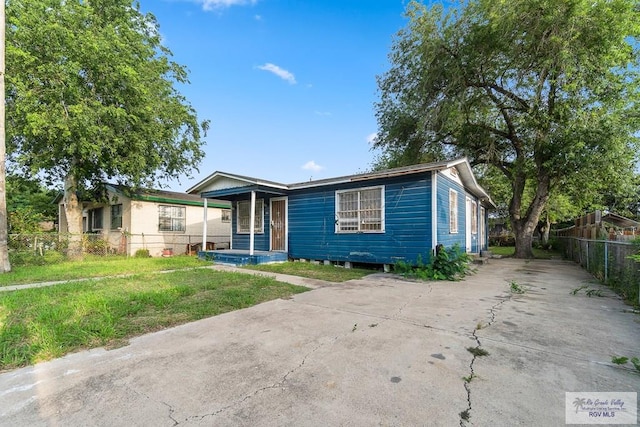 view of front of home featuring a porch, a front yard, driveway, and fence