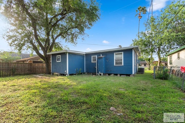 rear view of property with a lawn, central AC, and fence