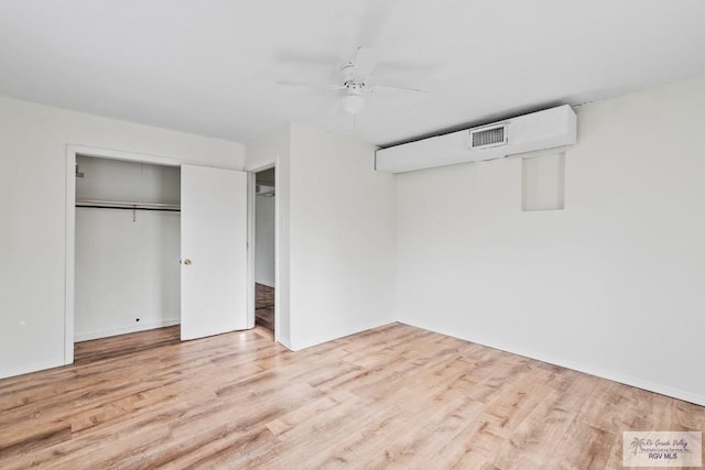 unfurnished bedroom featuring wood finished floors, baseboards, visible vents, and a closet