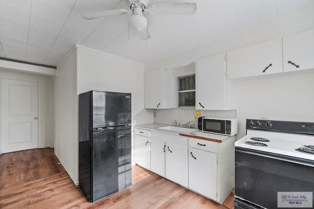 kitchen featuring light countertops, range with electric stovetop, freestanding refrigerator, and a sink