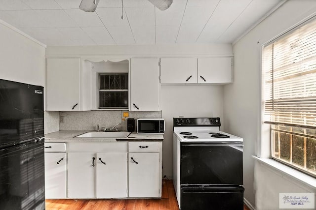 kitchen with range with electric cooktop, white cabinetry, tasteful backsplash, a sink, and light wood-style floors