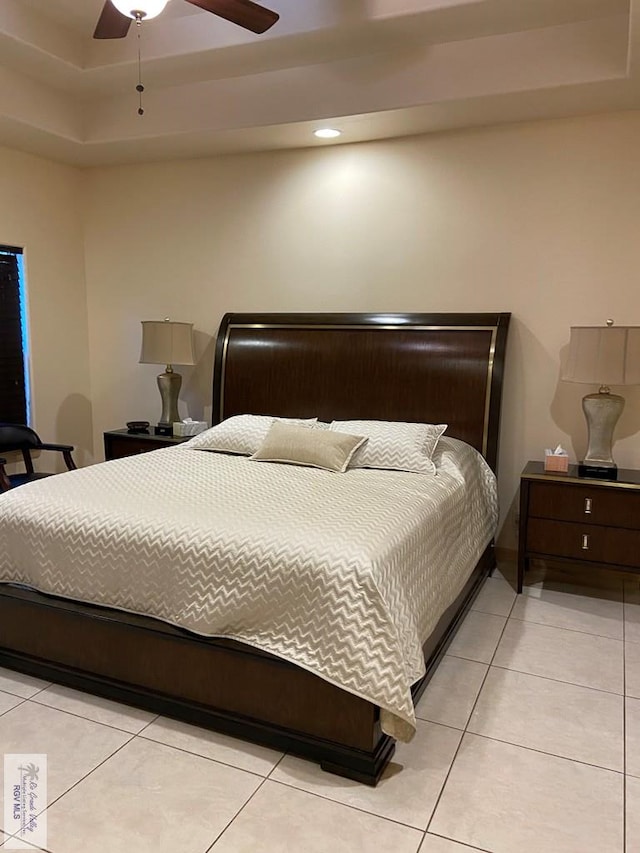 bedroom with light tile patterned floors, ceiling fan, and a raised ceiling