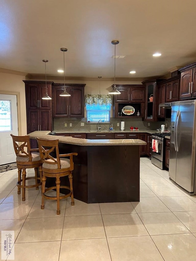 kitchen with sink, appliances with stainless steel finishes, dark brown cabinets, and decorative light fixtures