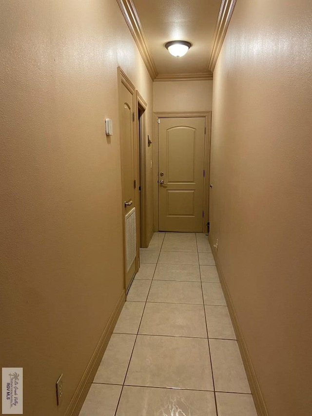 hall with ornamental molding and light tile patterned floors