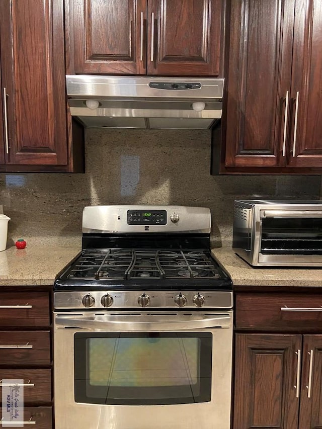 kitchen featuring backsplash, dark brown cabinets, stainless steel gas range oven, and light stone countertops