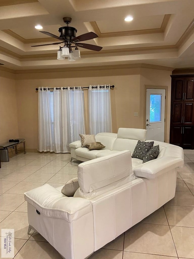 tiled living room with ceiling fan, a tray ceiling, and ornamental molding