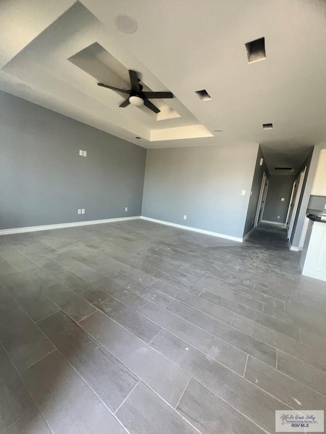 empty room with visible vents, a raised ceiling, baseboards, and ceiling fan