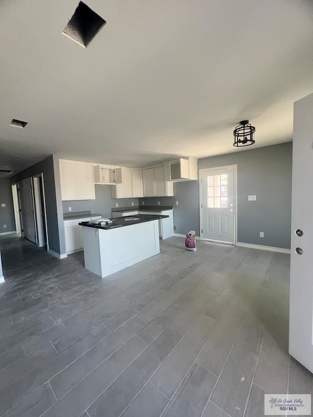 kitchen with dark countertops, open floor plan, a center island, and white cabinetry