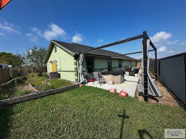 back of house featuring a lawn, a patio area, central air condition unit, and a hot tub