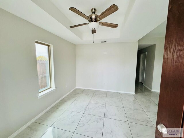 43 El Paso Rd, Brownsville, TX 78520 - spare room featuring a ceiling fan, baseboards, visible vents, a tray ceiling, and marble finish floor