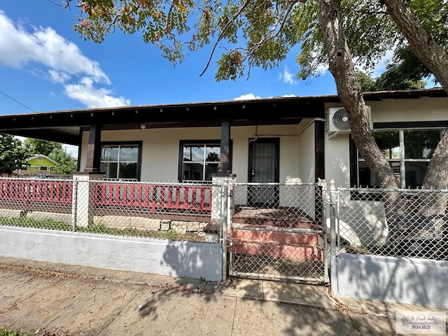 view of front of home featuring covered porch, a fenced front yard, a gate, and stucco siding