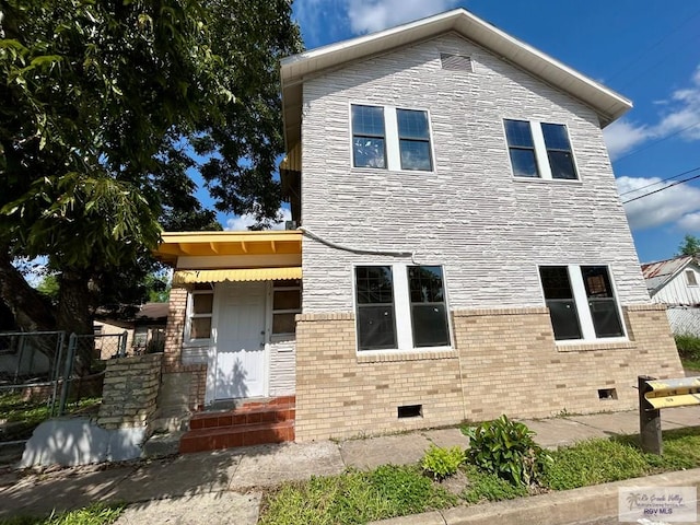 view of front of home featuring stone siding, crawl space, and fence